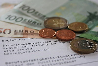 Foto: Über einem Rentenbescheid liegen Euroscheine und Münzen