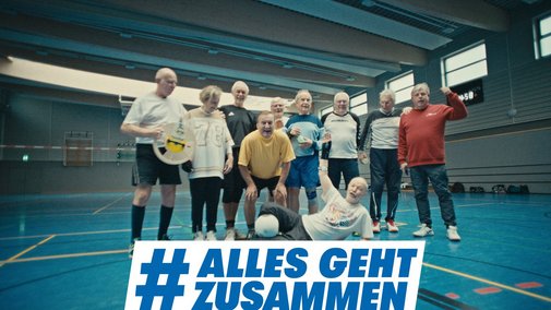 Alles geht zusammen - Gemeinschaft beim Sport Gruppenfoto einer Volleyballmannschaft, die aus älteren Sportlern besteht, in einer Turnhalle. Darüber das Logo der Aktion Alles geht zusammen.