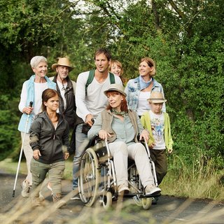 Eine Gruppe unterschiedlicher Menschen - mit und ohne Behinderung, alt und jung, Männer und Frauen - wandern gemeinsam im Grünen. 