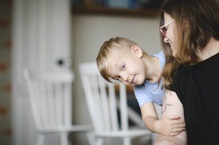 Das Bild zeigt einen Jungen im Kleinkindalter auf dem Arm seiner Mutter. 