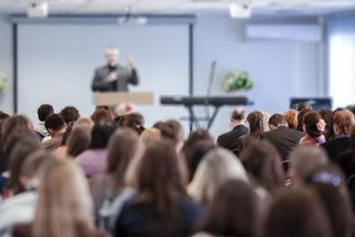 Konferenz: Männlicher Dozent spricht vor Gruppe von sitzenden Menschen