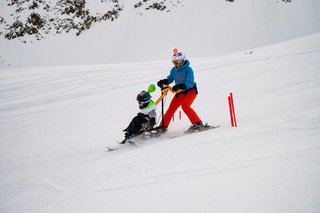 Auf dem Foto sieht man einen Biski-Teilnehmer in Begleitung auf der Piste.