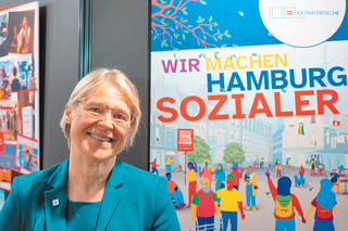 Ein Bild von Kristin Alheit vor dem Plakat: Wir machen Hamburg Sozialer.