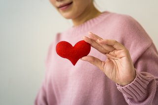 Eine Frau hält ein rotes Stoffherz in der Hand