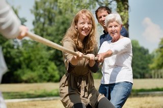 Zwei Frauen und ein Mann ziehen an einem Seil