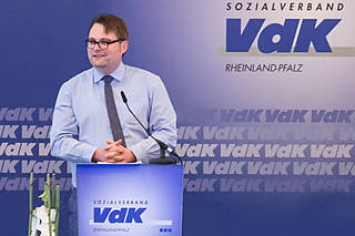 Ein Mann steht an einem Rednerpult mit dem VdK-Logo.