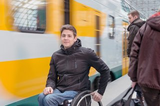 Mann im Rollstuhl auf einem Bahnsteig