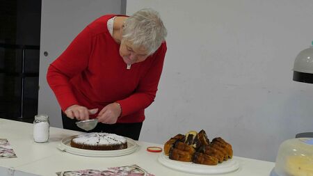 Eine Frau siebt Puderzucker auf einen Kuchen