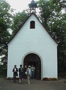 weiße Kapelle mit 4 Personen im Vordergrund