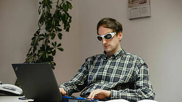 Foto: blinder Mann vor einem Computer