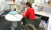 Symbolfoto: Eine Frau im Rollstuhl an ihrem Schreibtisch im Büro