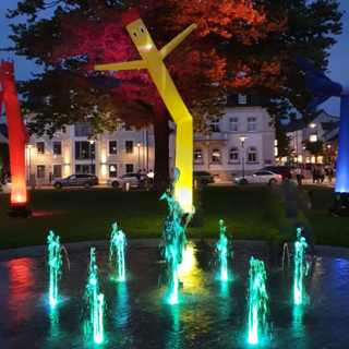 Zu sehen ist der blau beleuchtete Springbrunnen am Maxplatz