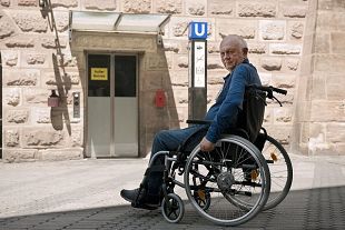 Ein Mann mit Rollstuhl steht vor einem Aufzug, der außer Betrieb ist