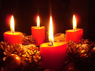 Foto: ein Adventskranz mit brennenden roten Kerzen