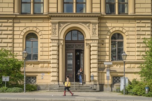 Fassade des Berliner Sozialgerichts, aus dem Eingang kommt gerade eine junge Frau. 