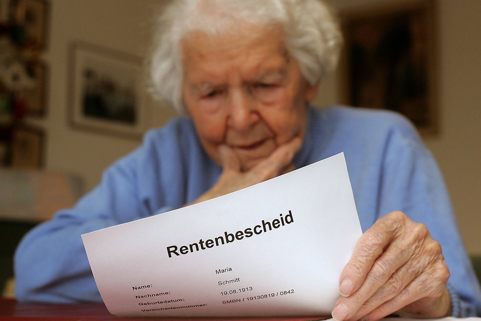 Seniorin liest Rentenbescheid Eine ältere Frau hält ein Dokument in der Hand, auf dem "Rentenbescheid" steht, sie wirkt besorgt oder ratlos.