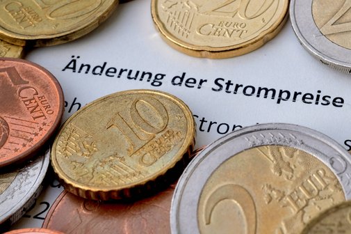 Ein Brief eines Energieversorgers, zu lesen ist "Änderung der Strompreise", darauf liegen Münzen