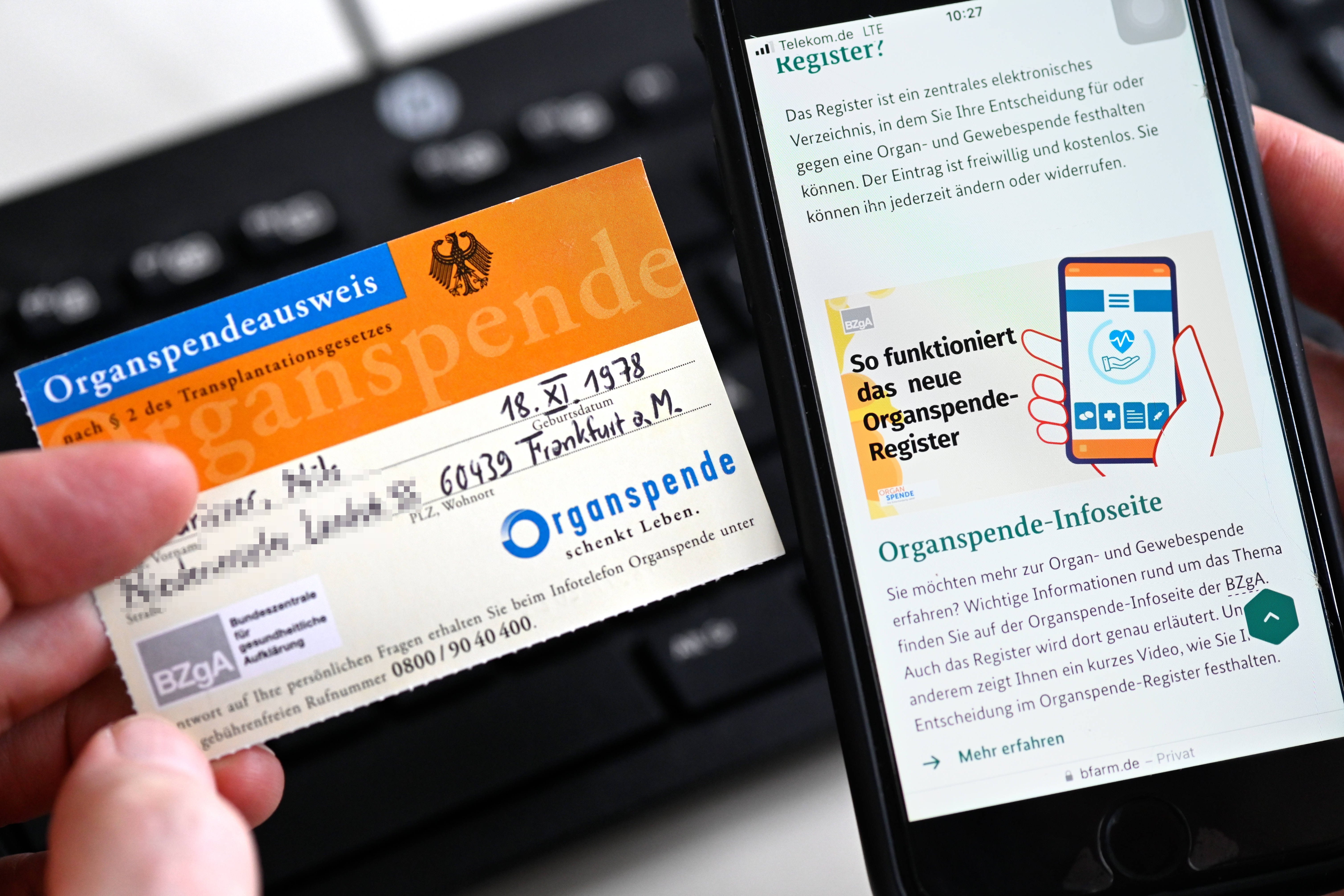Organspendeausweis und Organspenderegister Die Internetseite www.organspende-register.de auf einem Smartphone und ein Organspendeausweis