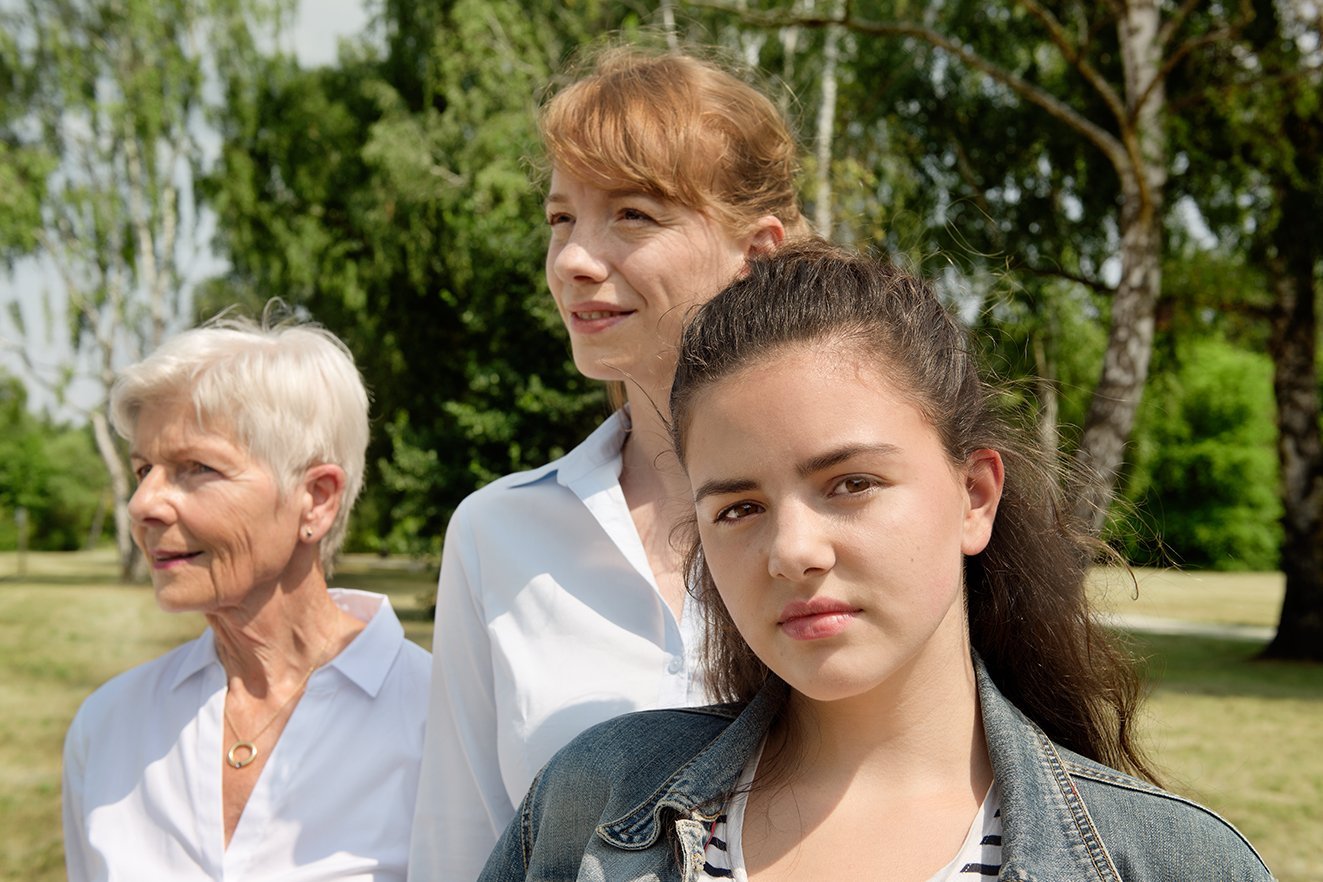 Frauen aus drei Generationen Drei Frauen - eine jüngere Frau und eine ältere Frau blicken in die Ferne, eine Teenagerin blickt ernst in die Kamera. .