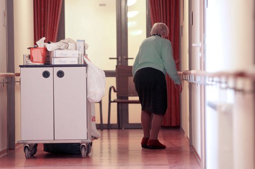 Bewohnerin einer Senioren-Residenz, sie geht über den Gang in ein Zimmer