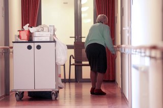 Bewohnerin eines Pflegeheims Bewohnerin einer Senioren-Residenz, sie geht über den Gang in ein Zimmer
