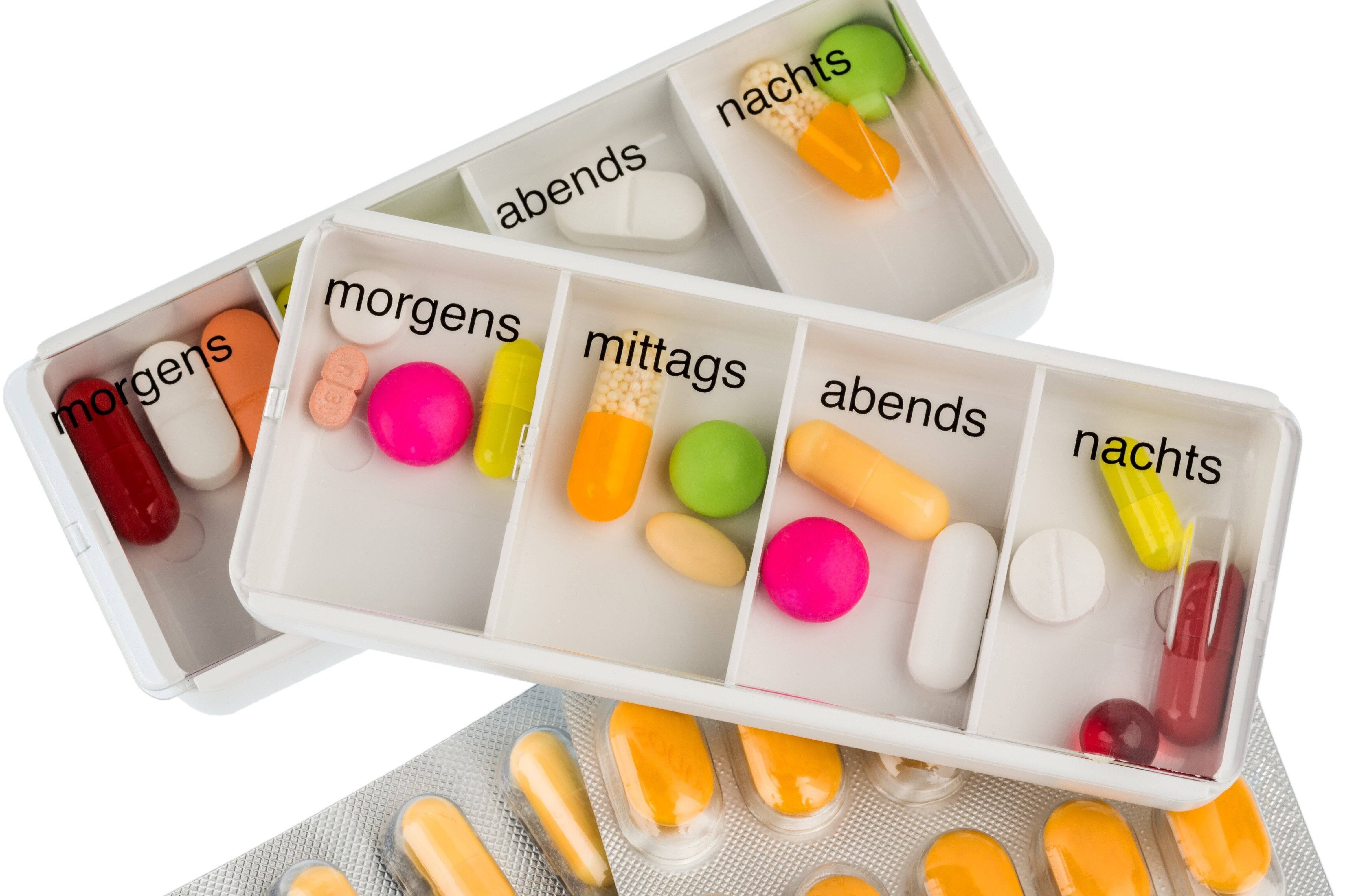 Ein Tablettenspender mit Fächern für morgens, mittags und abends. Darin sind viele bunte Pillen und Tabletten.