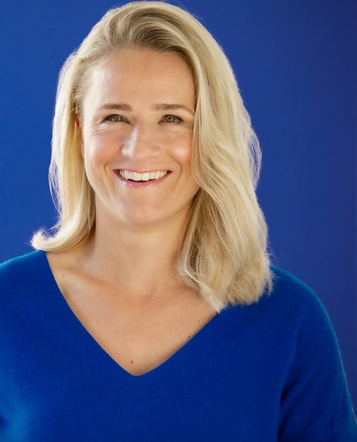 Das Portraitfoto zeigt Verena Bentele vor blauem Hintergrund, sie lacht in die Kamera