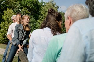 Gruppe von Männern und Frauen unterschiedlichen Alters gemeinsam auf einer Wippe.