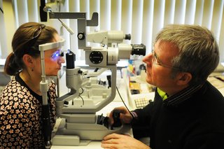 Ein Augenarzt führt eine Augeninnendruckmessung bei einer Patientin durch. 