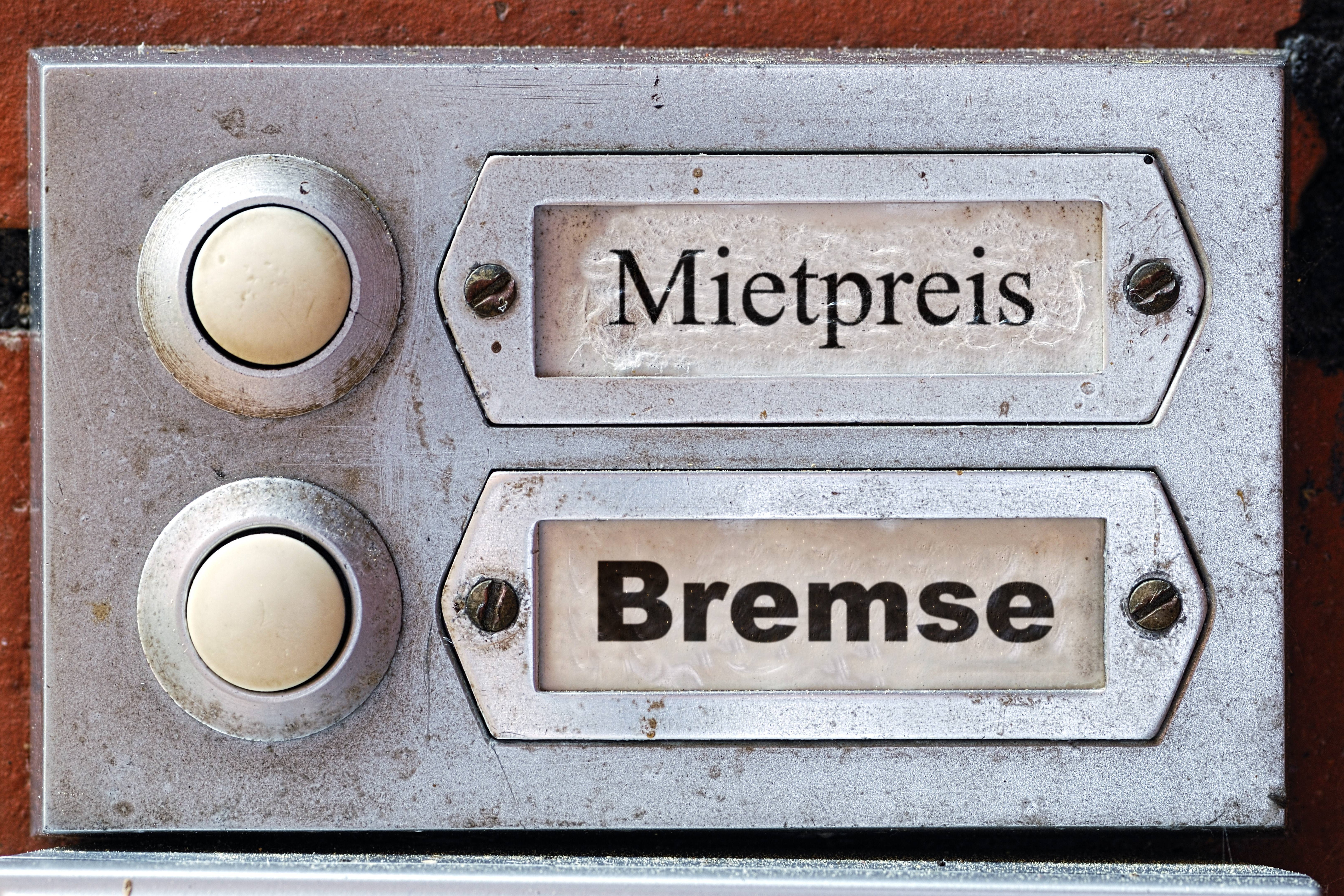 Mietpreisbremse Klingelschilder an einem Mietshaus, statt Namen stehen in den Klingelschildern die Worte "Mietpreis" und "Bremse."