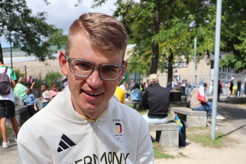 Maximilian Jäger sitzt auf einem Steinmäuerchen.
