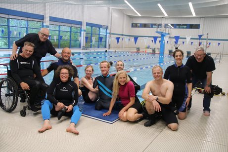 Mitglieder des 1. Berliner Inklusions-Tauchclubs Das Gruppenfoto zeigt die Mitglieder des Mitglieder des 1. Berliner Inklusions-Tauchclubs am Beckenrand im Schwimmbad.