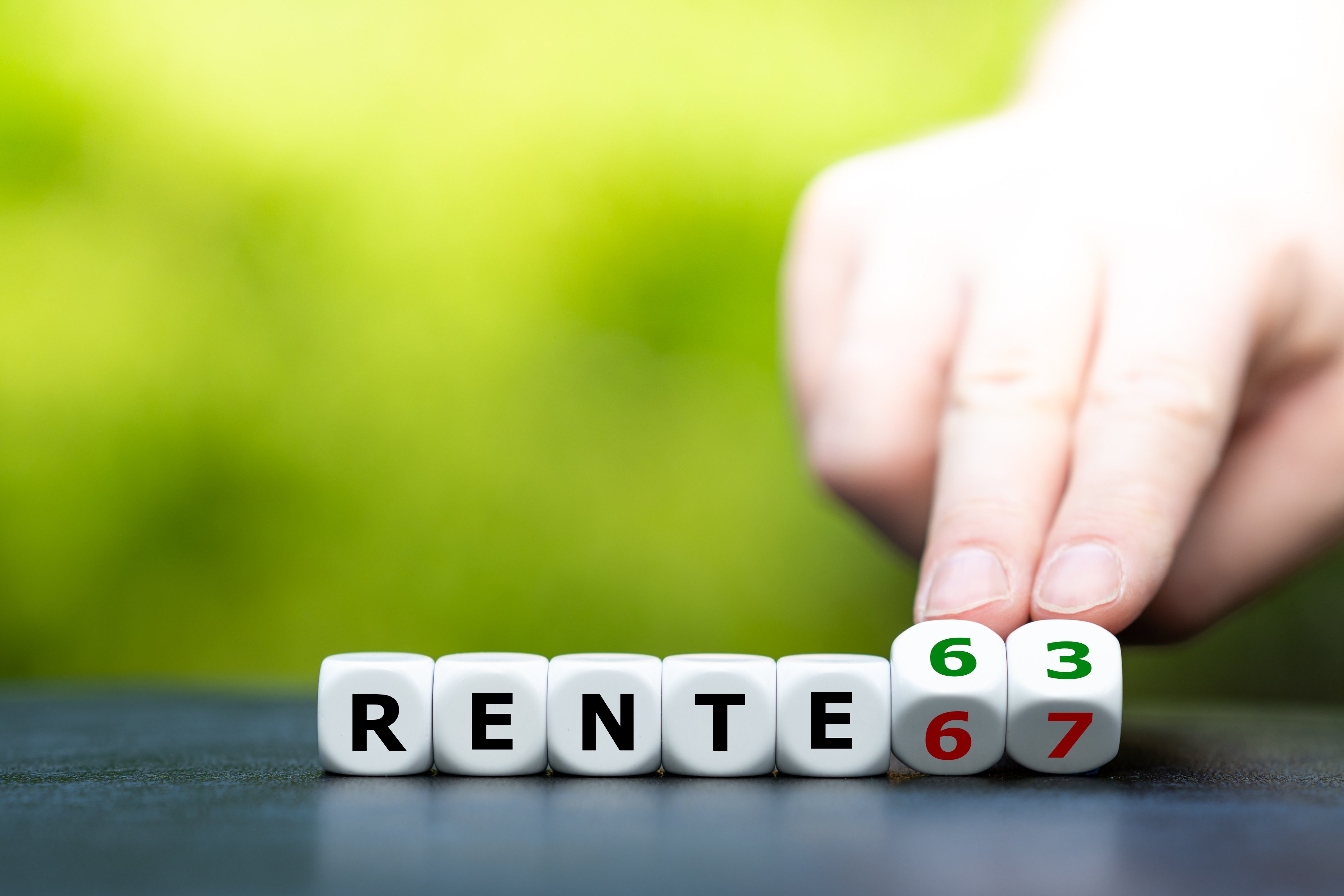 Rente mit 63 Rente mit 63 oder 67? Eine Hand dreht einen Buchstaben-/Zahlen-Würfel und ändert den Ausdruck "Rente 67" in "Rente 63"