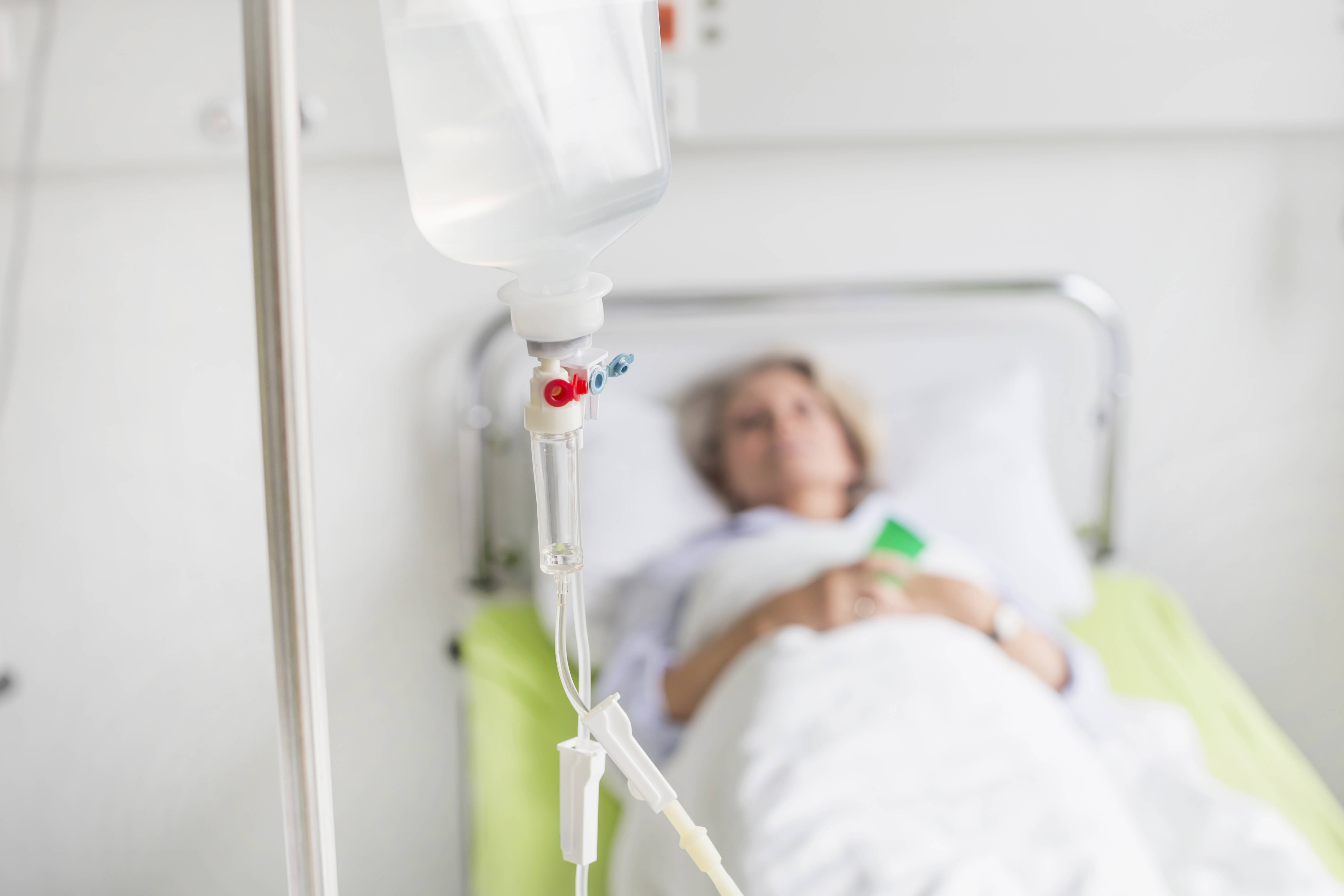 Frau im Krankenhausbett Eine Frau liegt in einem Krankenhausbett, im Vordergrund ein Tropf