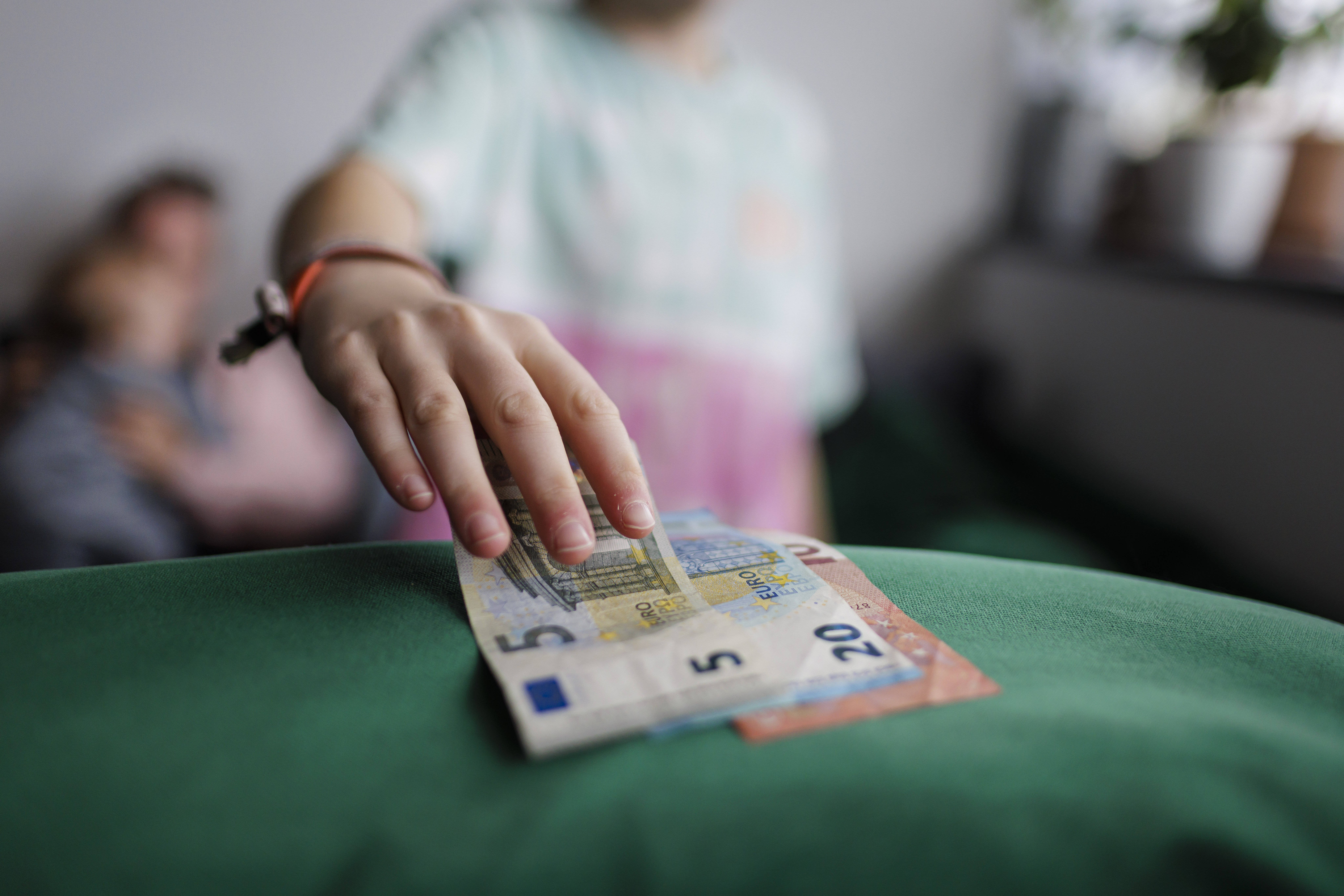 Kinderarmut Kinderhand greift nach Euro-Scheinen.