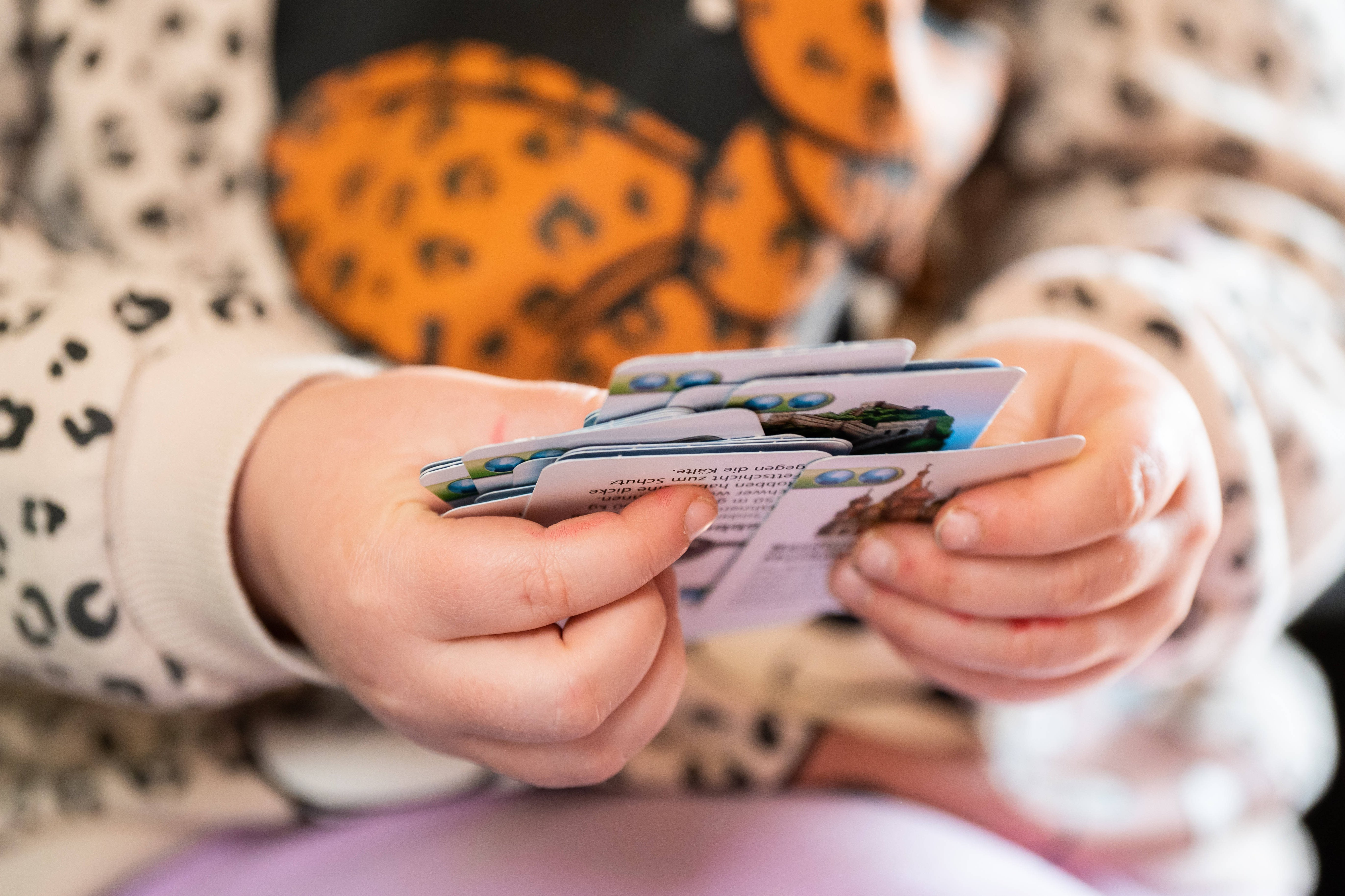 Ein Kleinkind hält Spielkarten für ein Kinderspiel in der Hand. 