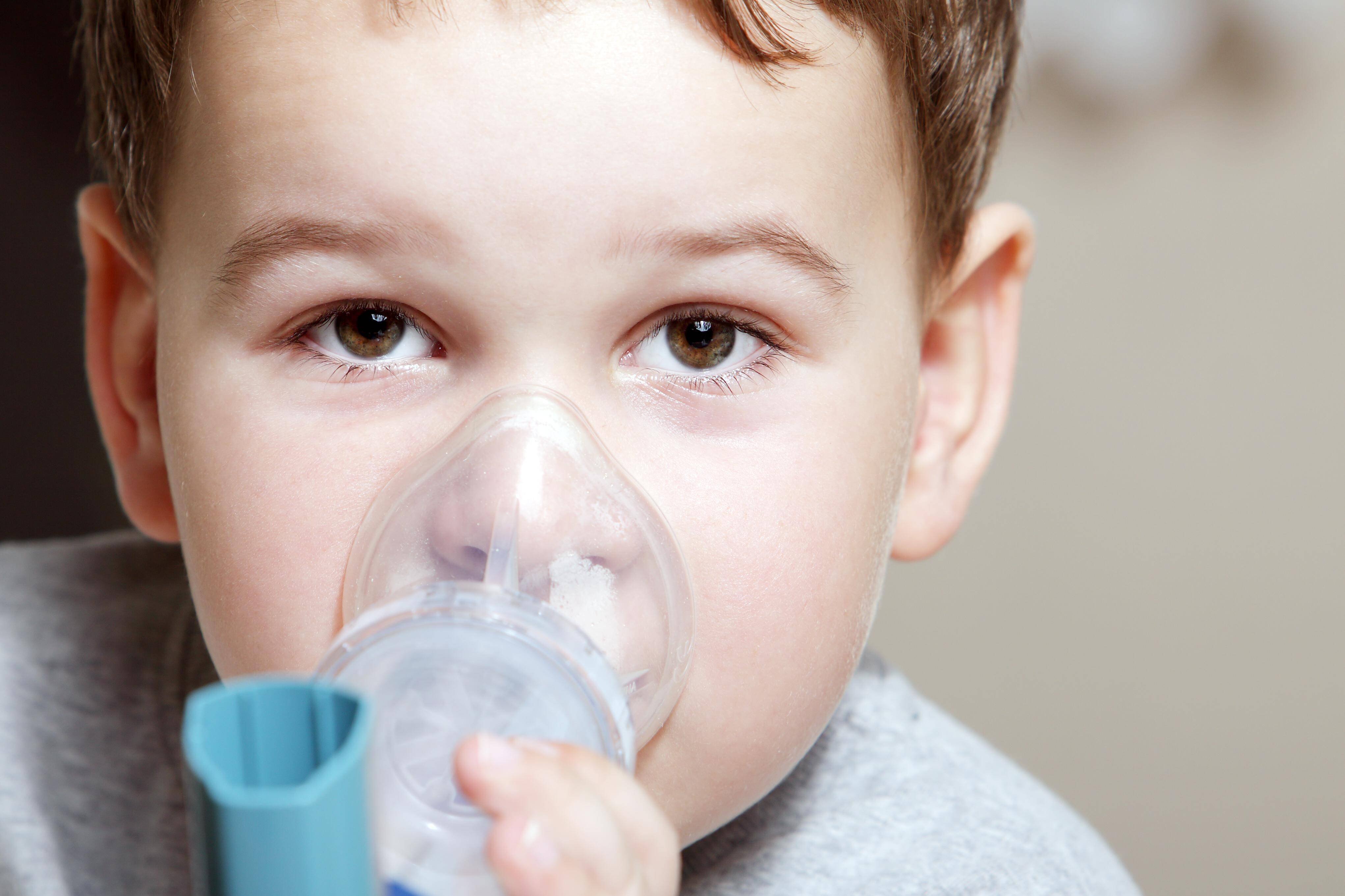 Kleiner Junge mit Inhalator Ein kleiner Junge hält sich einen Inhalator, wie er bei Asthma verwendet wird, über Mund und Nase.