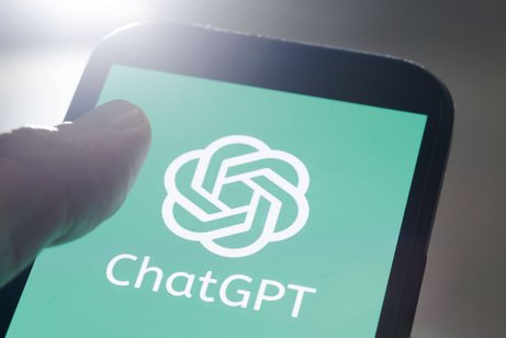 Jemand hält ein Smartphone, auf dem Display sieht man das Logo von ChatGPT
