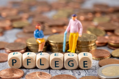 Seniorenfigürchen sitzen auf Münzstapeln, davor bilden Buchstabenwürfel das Wort Pflege