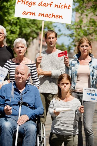 Gruppe von Menschen verschiedenen Geschlechts und Alters, mit und ohne Behinderung, demonstrieren. Auf einer Demopappe steht "Pflege darf nicht arm machen"