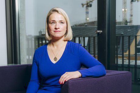 Verena Bentele sitzt auf einem Sofa, hinter ihr sieht man die Silhouette von Berlin.