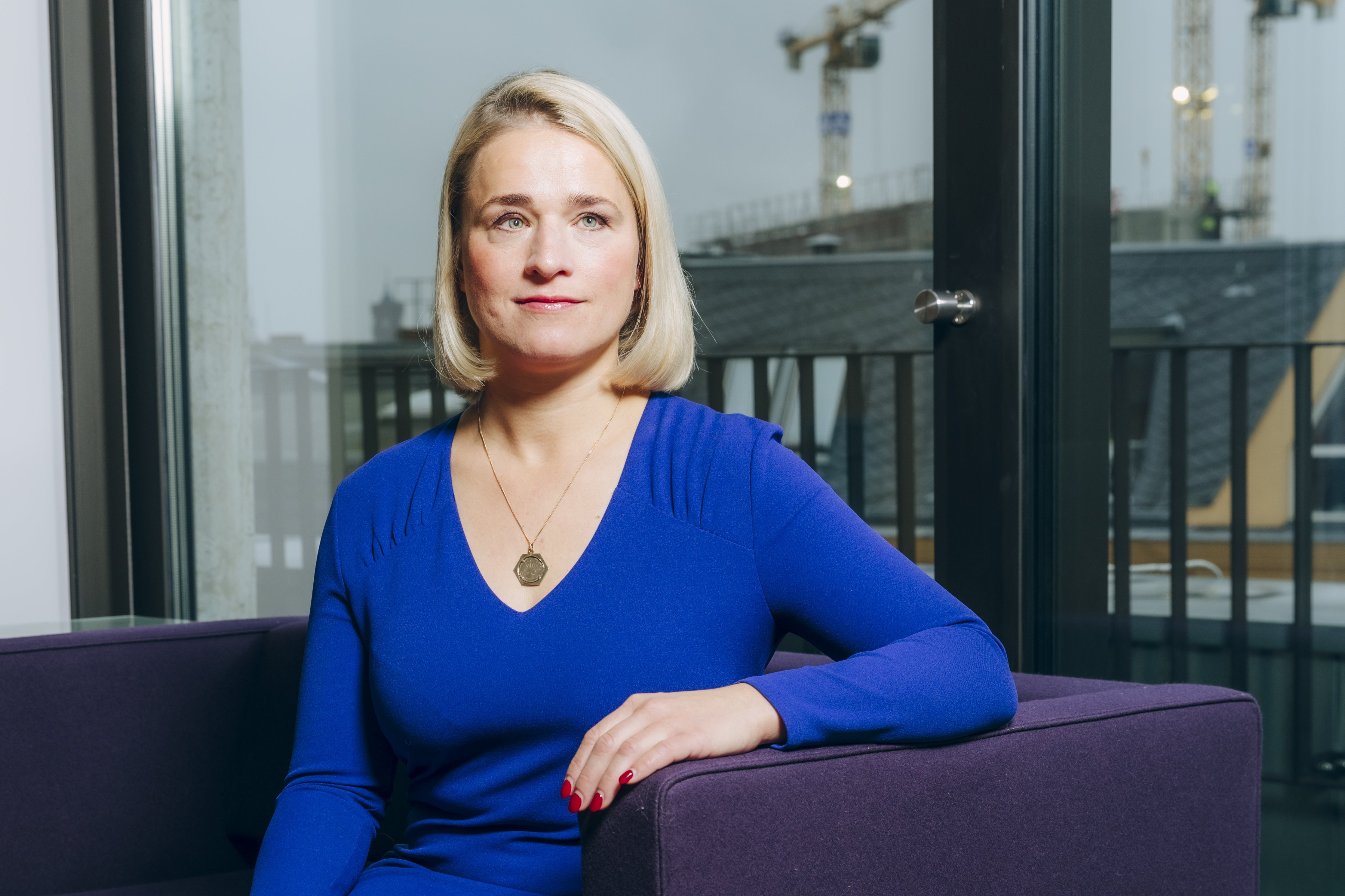 Verena Bentele Verena Bentele sitzt auf einem Sofa, hinter ihr sieht man die Silhouette von Berlin.