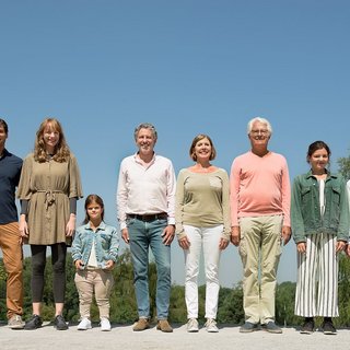 Menschen verschiedenen Alters, mit und ohne Behinderung, stehen lächelnd nebeneinander.