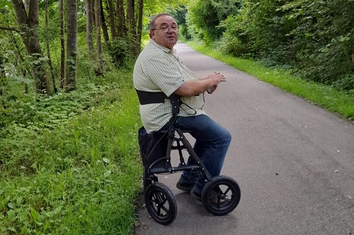 Friedbert Johannes auf einem Waldweg, er sitzt auf seinem Rollator.