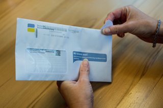 Hände einer Frau öffnen einen Brief der Deutschen Rentenversicherung 