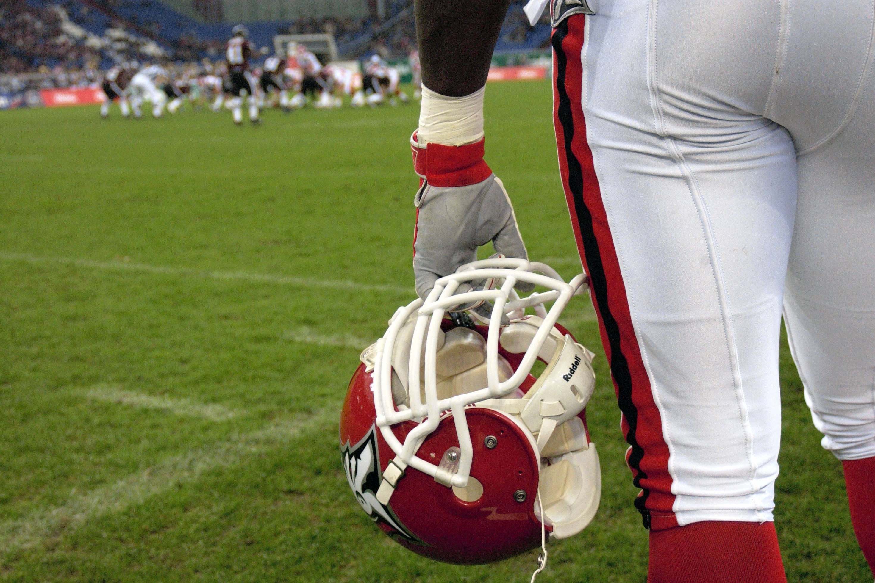 Football-Helm Ein Spieler der Cologne Centurions beobachtet das Spielgeschehen von der sideline American Football Herren NFL Europe League 2004. Er hält seinen Helm in der Hand.