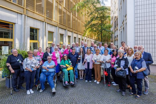 Gruppenfoto der ehrenamtlich Engagierten mit VdK-Präsidentin Verena Bentele im Innenhof des Kinos Delphi Lux in Berlin.