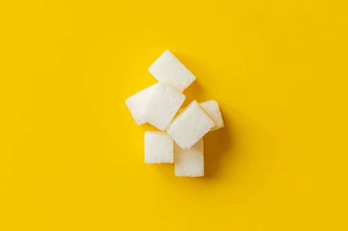Ein kleiner Berg aus Zuckerw&uuml;rfeln vor gelbem Hintergrund
