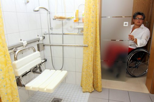 Frau im Rollstuhl an der Tür zu ihrem barrierefreien Badezimmer