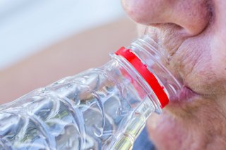 Eine ältere Frau trinkt Wasser aus einer Plastikflasche